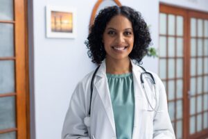 Portrait of happy biracial female doctor wearing stethoscope and smiling at doctor's office